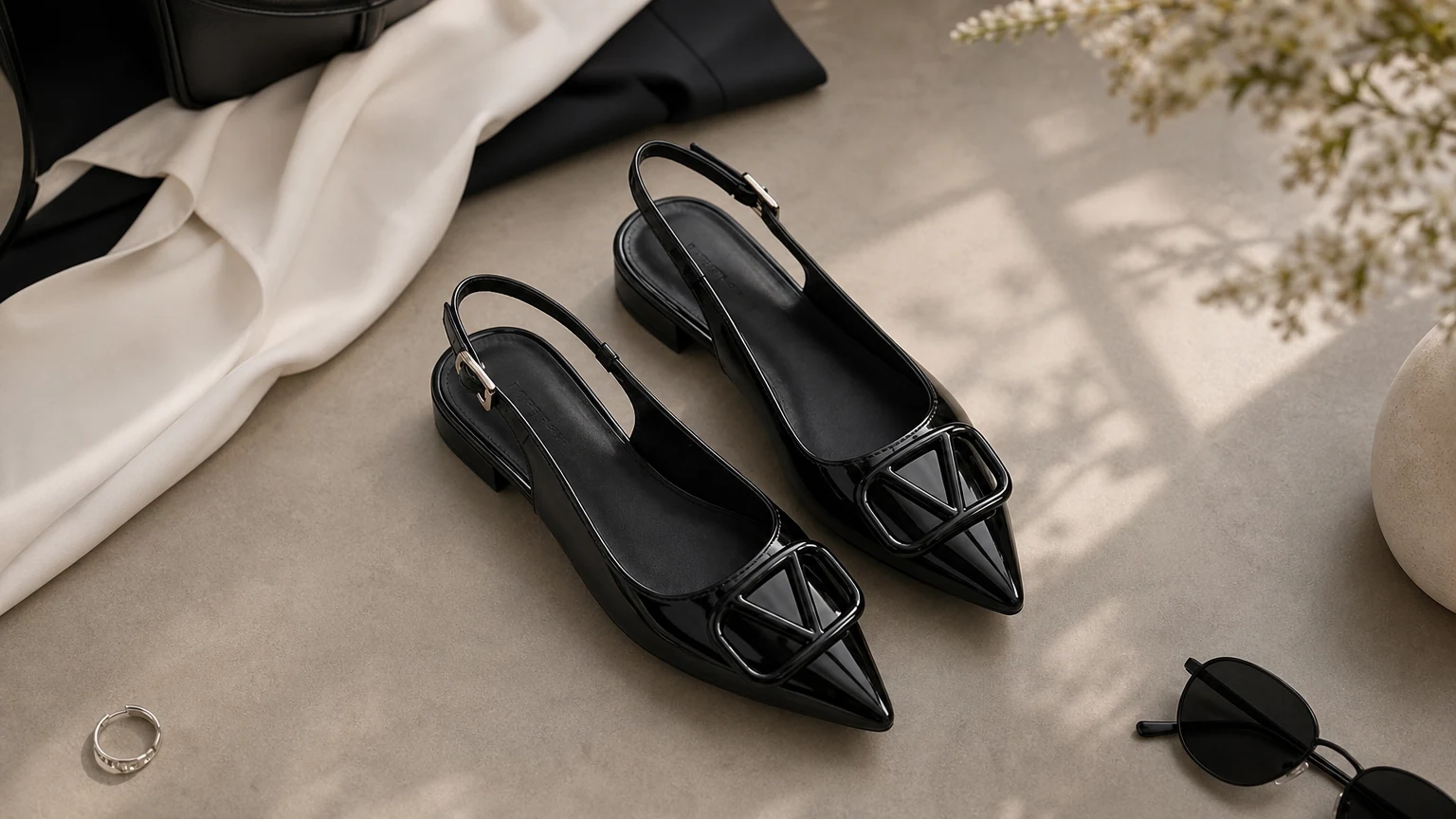 Zapatos planos destalonados con hebilla con apariencia de charol negros diseñados en una escena de moda horizontal