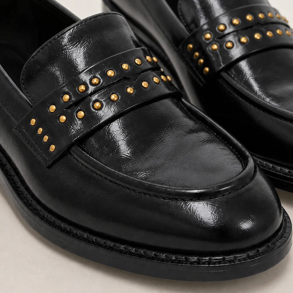 Détail en gros plan d'un mocassin noir brillant et d'une sangle cloutée