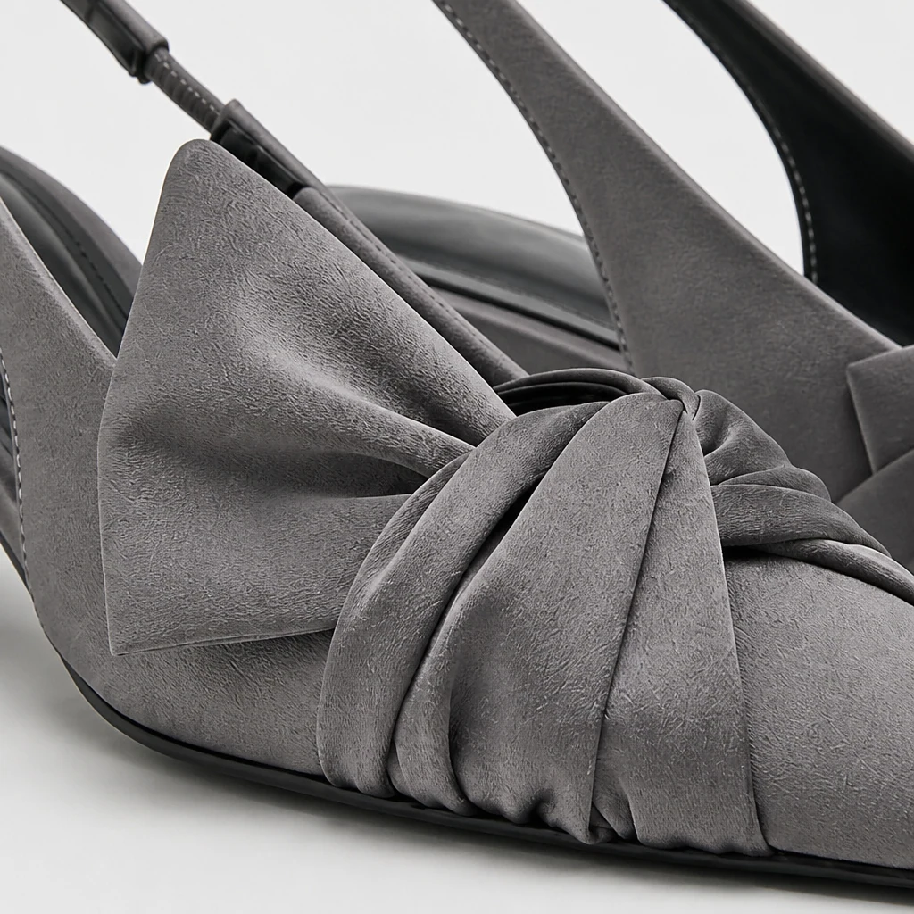 Primer plano del material del zapato de tacón gris, detalle de lazo, puntera puntiaguda y construcción del talón.